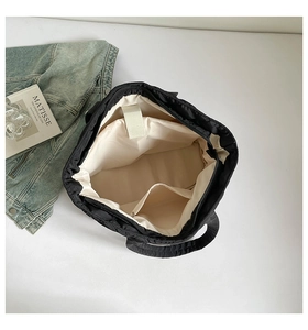 Detail view of black quilted tote bag interior showing beige lining and inner pocket