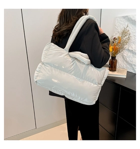 Detail of glossy quilted puffer tote bag with puffy padded texture on shoulder