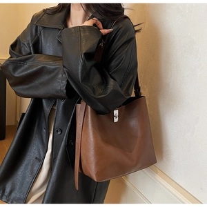Detail of brown leather bucket bag with silver square clasp and adjustable strap