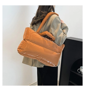 Close-up of vibrant orange quilted puffer bag with plush padded texture and carry handle