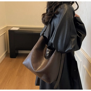 Detail of dark brown leather tote bag with silver twist lock shown on a female model