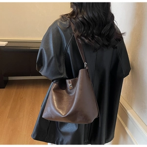 Detail of a dark brown leather shoulder bag with a silver rotating metal lock clasp