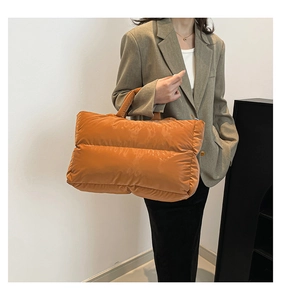 Detail of bright orange puffy tote bag with stitched padded texture and soft handle