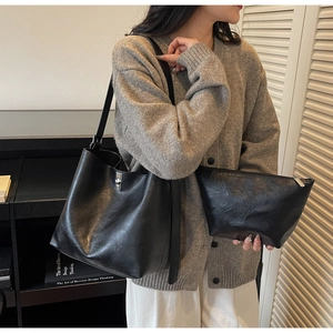 Detail of black leather tote bag with matching pouch and adjustable shoulder strap