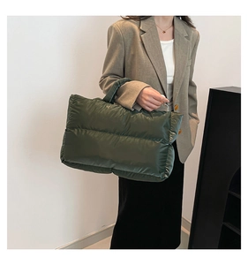 Detail of dark green quilted padded handbag with glossy nylon fabric and wide stitching