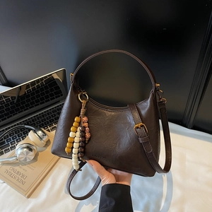 Sac croissant en cuir marron avec perles décoratives sur bureau avec ordinateur