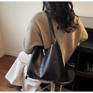 Detail of large black leather bucket bag with silver metal twist lock and shoulder strap