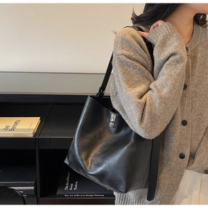 Detail of minimalist black leather bucket bag with silver buckle on shoulder
