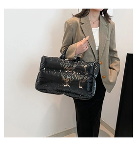 Close-up of black quilted puffer tote bag with glossy finish on a stylish model