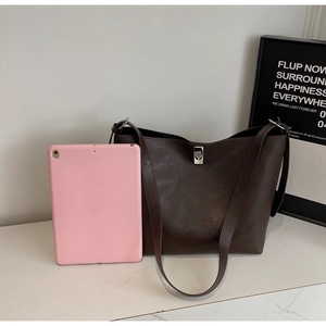 Detail view of large dark brown tote bag with silver twist lock and pink tablet for scale