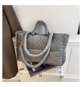 Detailed view of grey puffer tote bag featuring quilted nylon and padded handles