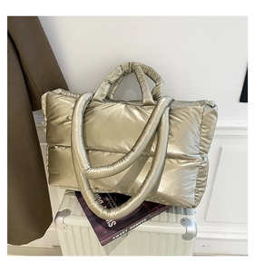 Macro view of metallic gold quilted puffer tote bag with glossy finish and soft handles