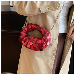 Macro view of a red sequined clutch bag with a unique twisted knot handle and chain