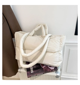 Detail view of the soft white quilted nylon handbag texture on a stylish travel suitcase