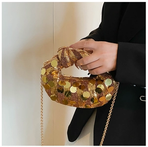 Detail of gold sequin evening bag featuring knot handle and metallic chain strap