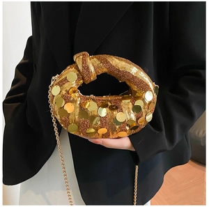 Close-up of golden sequin evening bag with knot handle and elegant metal chain