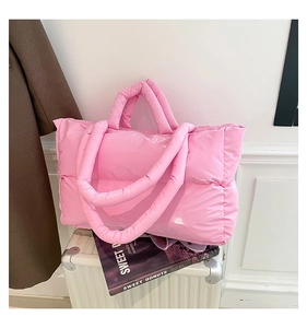 Pink quilted down tote bag placed on white luggage with aesthetic lifestyle props