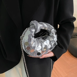 Detail of silver sequin clutch bag featuring a knot handle and elegant metal chain strap