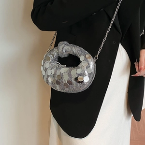 Silver sequin knot evening bag with metallic chain strap worn over a black blazer