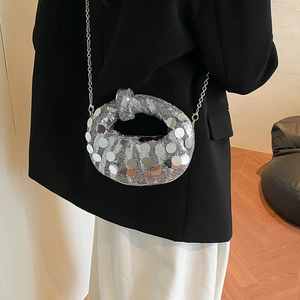 Detail of silver sequin bag with unique knot handle design and stylish metal chain strap
