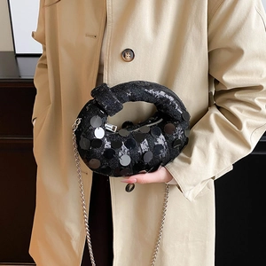 Close-up of black sequined knot evening bag with shimmering texture and silver chain strap