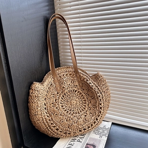 Handcrafted round straw handbag with leather handles and textured weaving for summer style