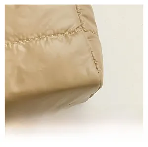 Close-up of beige quilted fabric with premium stitching on a padded shoulder bag