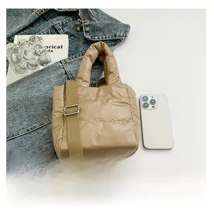 Top view of beige quilted puffer bag with adjustable shoulder strap and fashion props