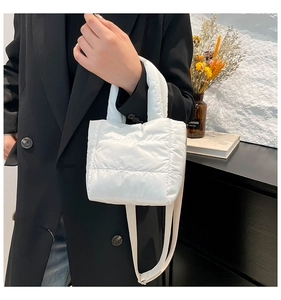 Detailed view of white quilted down-filled crossbody bag with puffy handle and strap