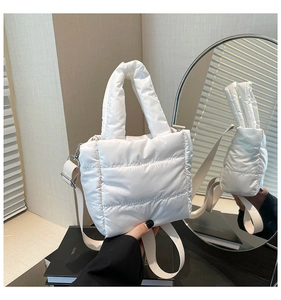 Detail of white quilted puffer handbag showing the thick handle and detachable strap