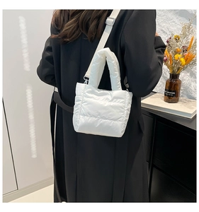 Detail showing white quilted puffer bag texture with adjustable fabric shoulder strap