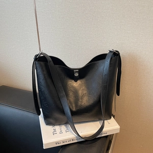 Minimalist black leather tote bag with silver buckle and wide shoulder strap