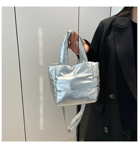 Detail of silver metallic quilted puffer bag with horizontal stitching and shoulder strap