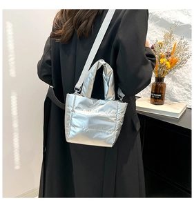 Detailed view of silver quilted tote bag with detachable strap worn on black coat