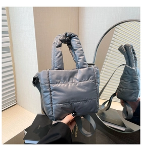 Detail of grey quilted down tote bag with thick handles and adjustable fabric strap