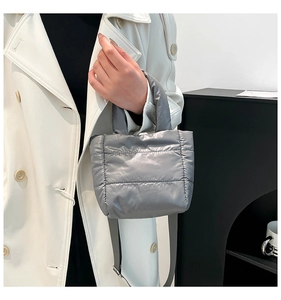 Detailed macro view of silver quilted down nylon handbag with adjustable grey shoulder strap