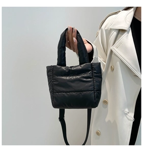 Detail of black quilted puffer bag with crossbody strap and matching soft handle
