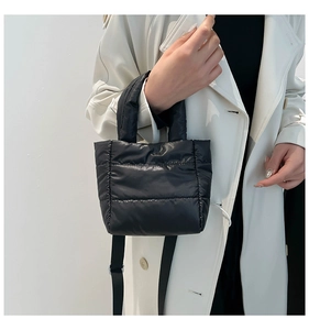 Detail of black quilted puffer bag with adjustable woven strap and soft nylon texture