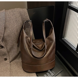 Close-up of a large dark brown leather tote bag with retro matte texture and stitching detail