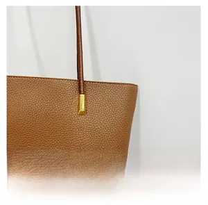 Gros plan détaillé sur le cuir grainé marron et les boucles dorées du sac à main