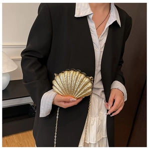 Mini sac de soirée en forme de coquillage doré avec chaîne, porté par un mannequin