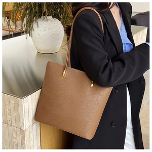 Sac cabas marron en cuir grainé avec détails métalliques dorés porté à l'épaule