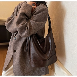 Detail of a dark brown large leather hobo shoulder bag styled with a tweed blazer