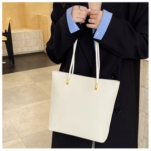 Détail d'un sac cabas blanc cassé avec cuir grainé et boucles dorées élégantes