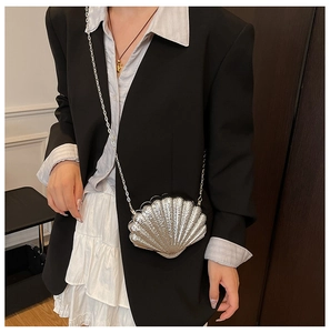 Détail du mini sac argenté en forme de coquillage avec bandoulière sur robe fleurie