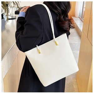 Détail de la texture cuir grainé blanc et boucles dorées sur la bandoulière du sac