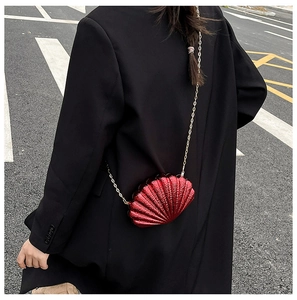 Détail du mini sac coquille rouge avec paillettes et bandoulière chaîne dorée à l'épaule