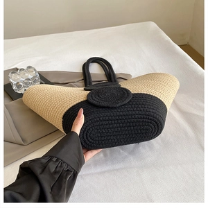 Detail of handmade woven tote bag showing beige and black stitching with textured finish