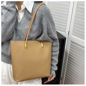 Détail du sac cabas en cuir grainé marron avec attaches dorées pour la bandoulière