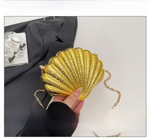Détail d'une pochette de soirée dorée en forme de coquillage avec texture métallique fine